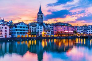 Zurich riverside view at dusk, colourful buildings and sunset reflected in the water