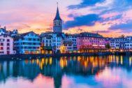 Zurich riverside view at dusk, colourful buildings and sunset reflected in the water