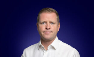 Paul Marshall, Head of IT, dressed in a white shirt and smiling at the camera