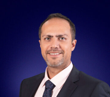 Edouard Senhaji, Head of Sophis Services, a dark-haired professional smiling at the camera against a wide blue header