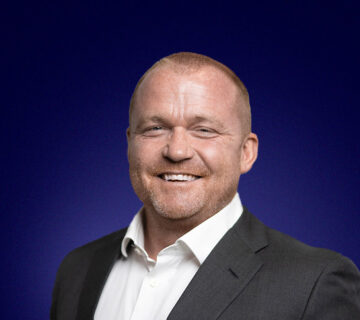 Desmond Stockdale, Founder and CEO a light haired man in a dark suit, smiles at the camera
