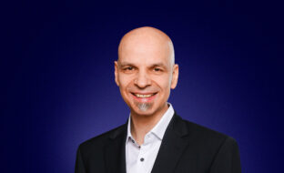 Christoph Steigemann, Head of Managed Services, dressed in a dark suit, smiling at the camera