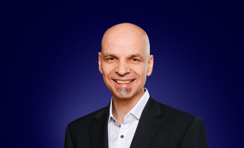 Christoph Steigemann, Head of Managed Services, dressed in a dark suit, smiling at the camera