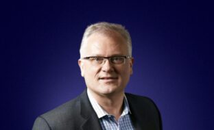 Headshot of Tom Kozlowski, Phi Board Member, in front of blue background