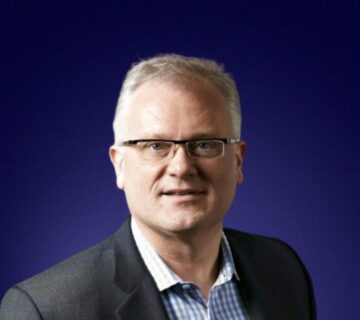 Headshot of Tom Kozlowski, Phi Board Member, in front of blue background