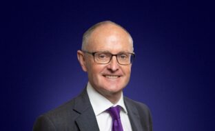 Headshot of Chris Harper, Strategic Advisor, in front of blue background