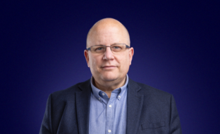 Chief Business Operations Officer, Daren Whybrow, in front of a blue background