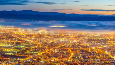 Sofia lit up at dusk with mist and mountains in the background