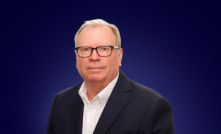 Strategic Advisor Andrew Skehel in front of a blue background